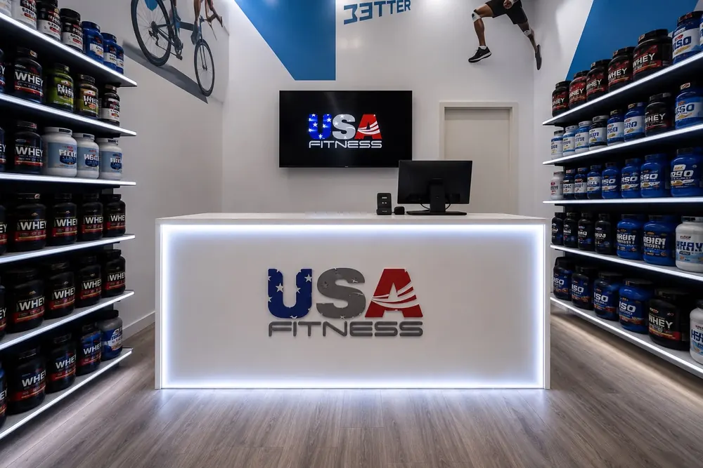 Mostrador de USA Fitness rodeado de estanterías de proteínas